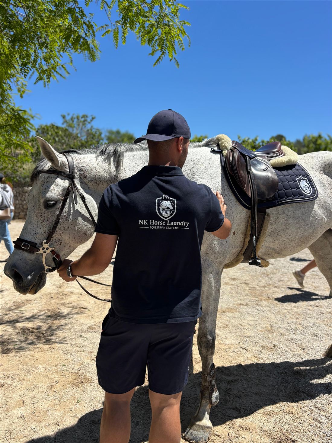 Sudadero azul con el escudo NK bajo la silla de un caballo tordo